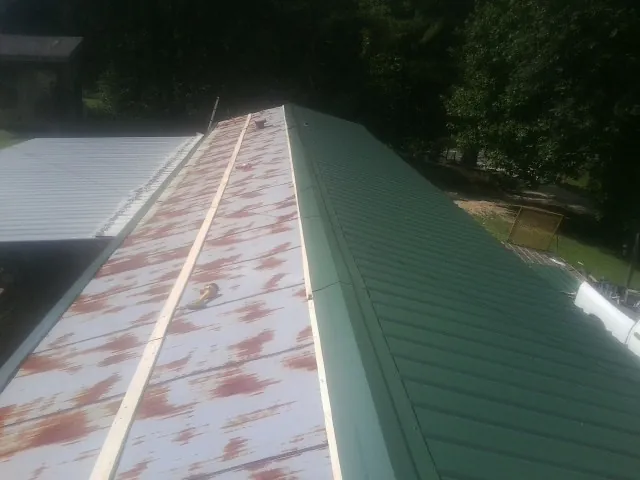 Old rusted panels beside newly installed green metal roofing — Wind Damage Roof Repair by Roofing Brothers in Whitewater