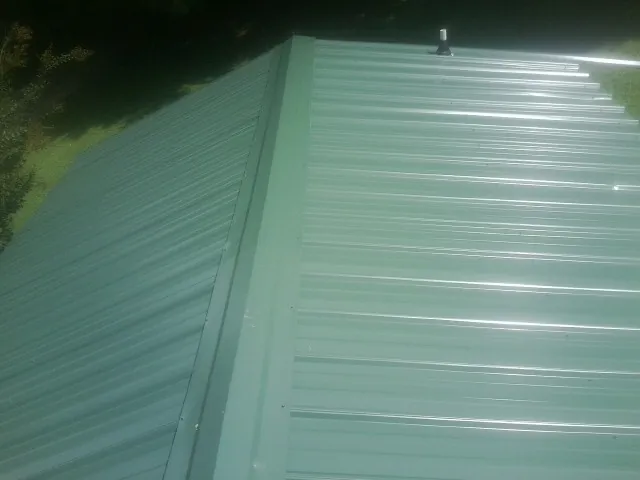New green metal panels meeting at the ridge of a roof — Flat Roof Repair work by our crew in Whitewater