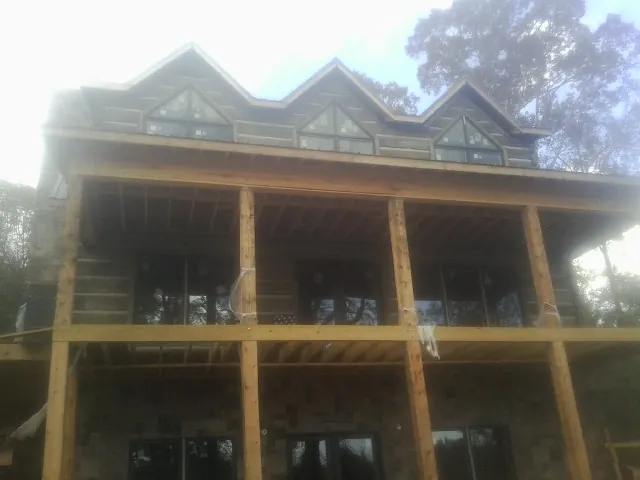 Dormers and porch framing on a large log home under construction — Roof Coating work by our crew in Whitewater