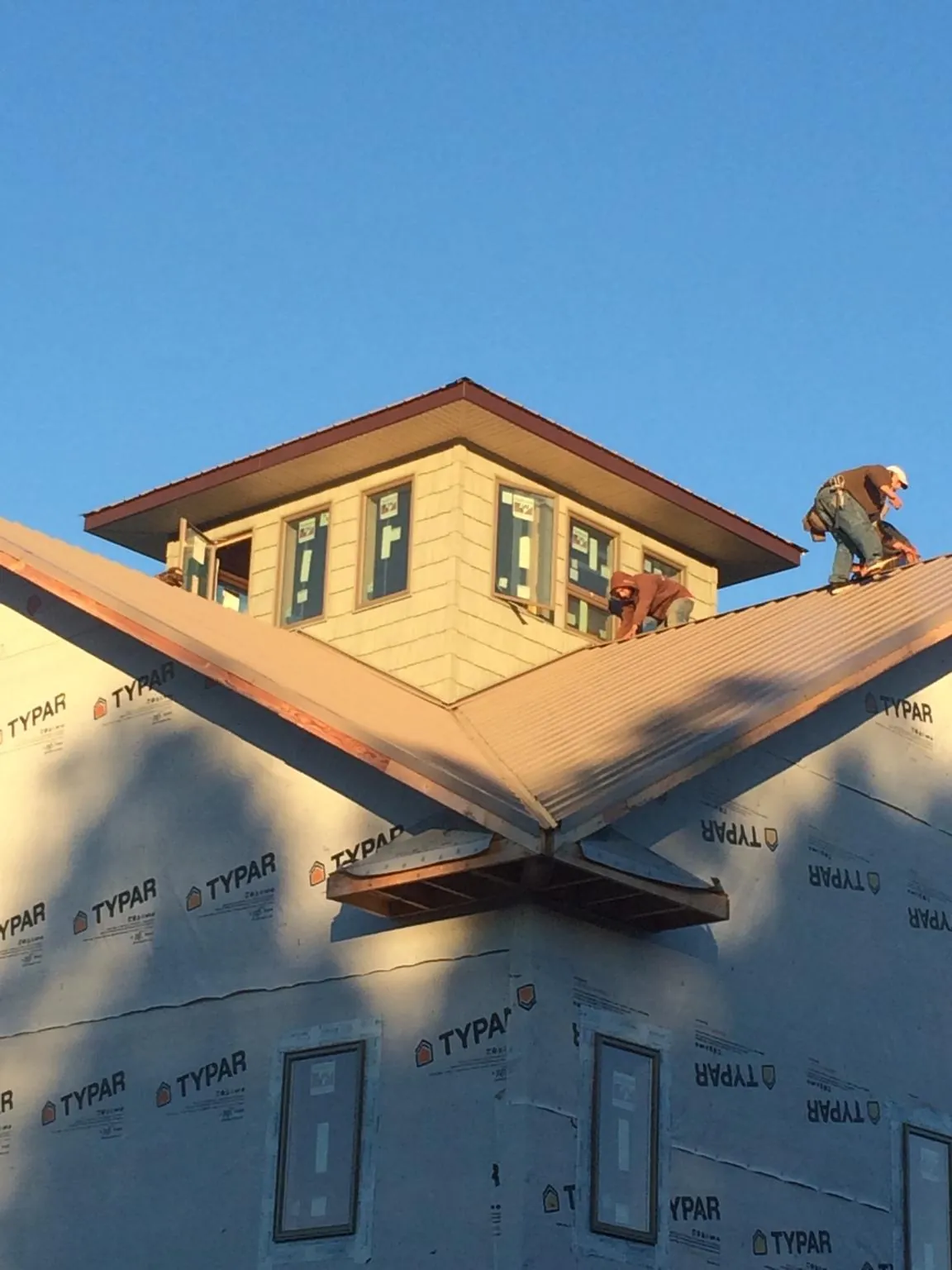 Roofers working around a rooftop cupola on a new metal roof at sunset — Roof Waterproofing in Whitewater by Roofing Brothers